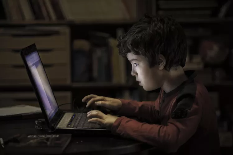 Kid watching laptop in night 